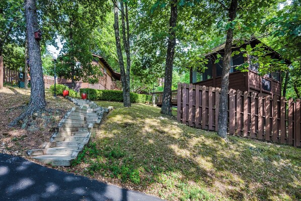 A wooden cabin with a wooden deck and a staircase leading to a porch. - 1 Bedroom Cabin In The Woods, Covered Porch, Jacuzzi, Kitchen & Hot Tub. (Eureka Springs)