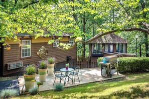 A cozy outdoor patio with a wooden deck, a small table with chairs, and a barbecue grill.