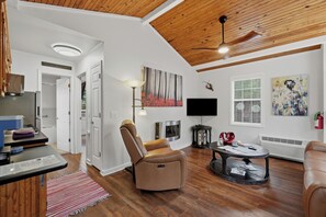 Una sala de estar moderna con un sillón de cuero marrón, un televisor de pantalla plana y una chimenea.