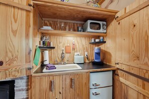 Una cocina compacta con armarios de madera, microondas, tostadora y cafetera.