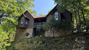 A two-story house with a stone foundation, a balcony, and a wooden roof. - 1 Bedroom Cabin In The Woods, Covered Porch, Jacuzzi, Kitchenette and Hot Tub. (Eureka Springs)