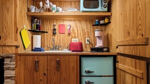Une cuisine compacte dotée de meubles en bois, d’un four à micro-ondes, d’une machine à café et d’un petit réfrigérateur.
