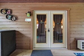 A wooden building entrance with a double door, a sign reading 'Magnolia', and a wall-mounted clock. - 1 Bedroom Cabin In The Woods, Covered Porch, Jacuzzi, Kitchenette and Hot Tub. (Eureka Springs)