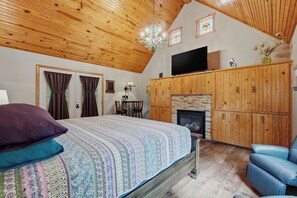 A bedroom with a bed, a television, a fireplace, and a seating area. - 1 Bedroom Cabin In The Woods, Covered Porch, Jacuzzi, Kitchenette and Hot Tub. (Eureka Springs)