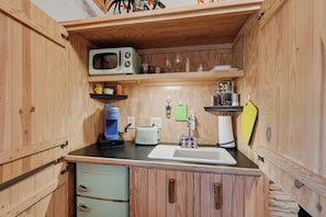 Una cocina compacta con armarios de madera, microondas, tostadora y cafetera.