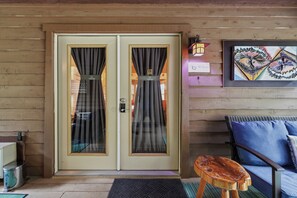 Una puerta de madera con un panel de vidrio, un taburete de madera pequeño y un sofá azul.