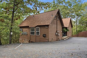 A wooden cabin with a pitched roof, labeled 'The Woods,' surrounded by trees.