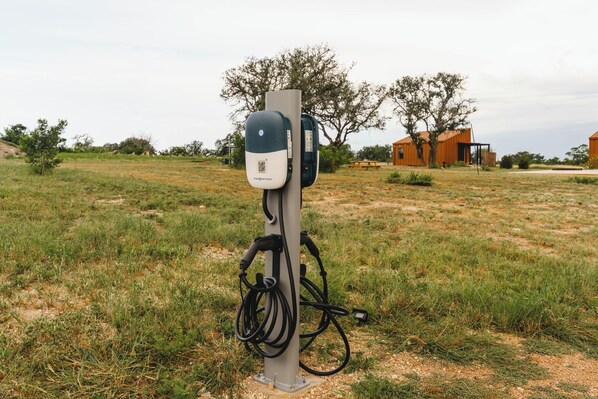 Una estación de carga para vehículos eléctricos en un campo cubierto de césped, con un edificio al fondo.