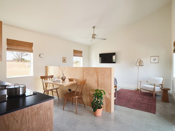 A modern kitchen with a dining area, a wooden partition, and a large window.
