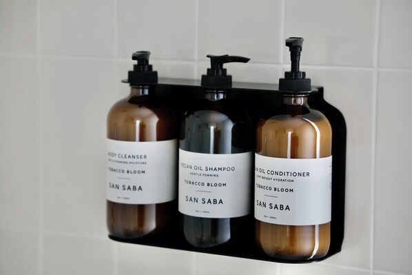 Three bottles of San Saba body care products on a black shelf. - Luxury cabin in the center of the Texas Wine Country; large private porch w/hot tub, gas grill and fire pit; pet friendly (Stonewall)