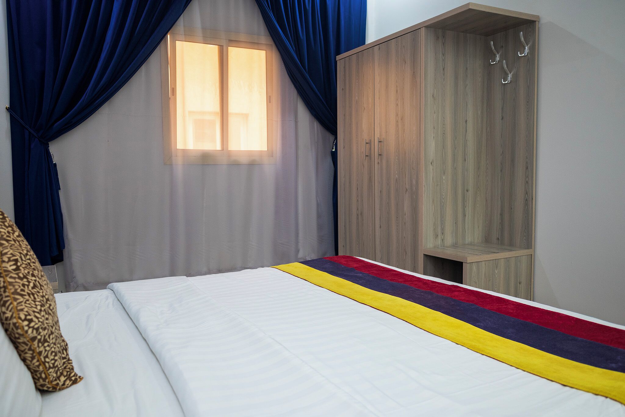 A bedroom with a bed, a wardrobe, and a window with curtains.