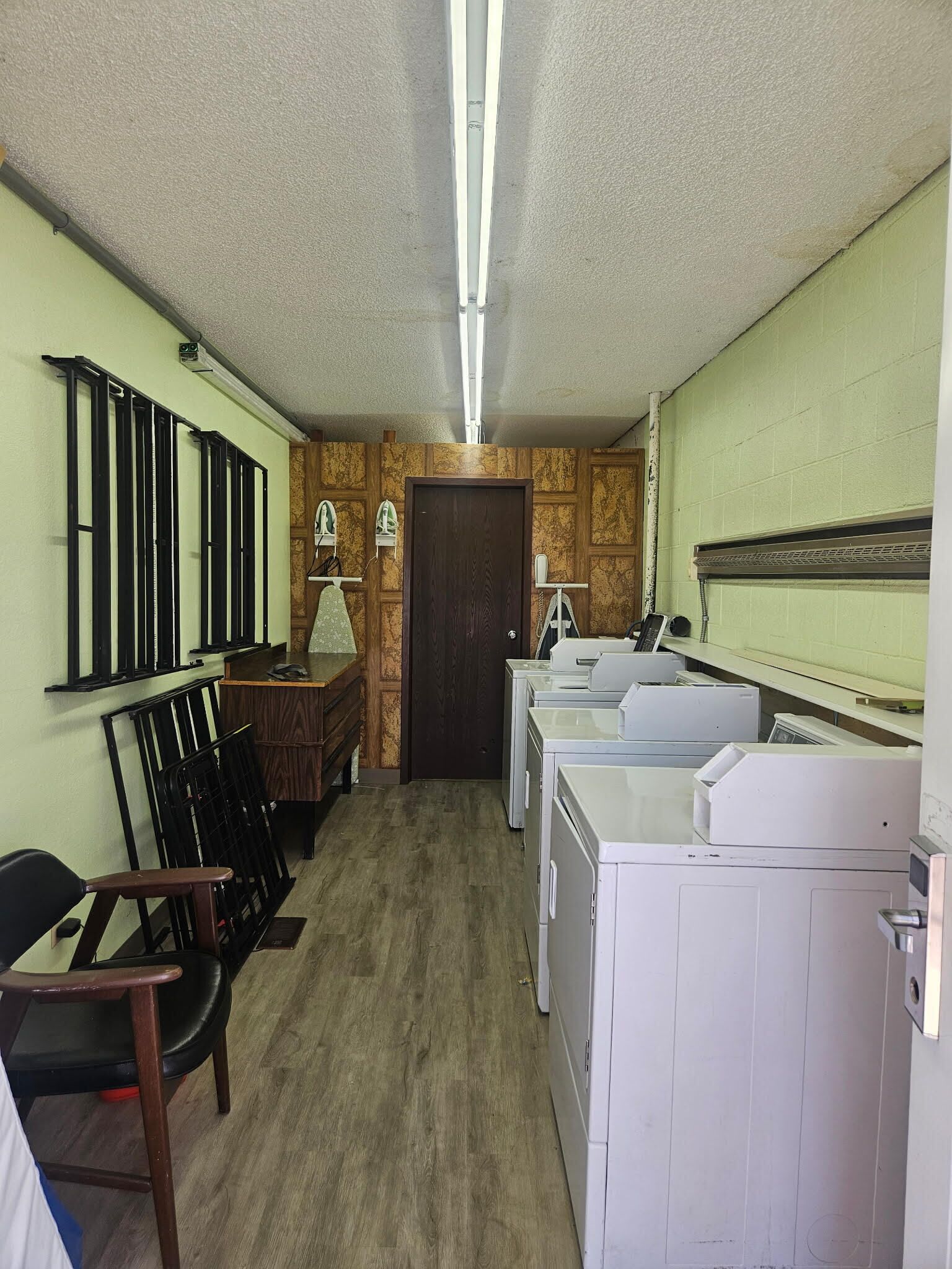 Un cuarto de lavandería con un banco de madera, un escritorio y varias lavadoras.