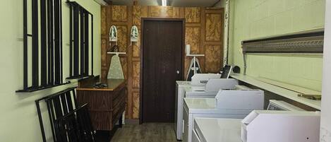Un cuarto de lavandería con un banco de madera, un escritorio y varias lavadoras.