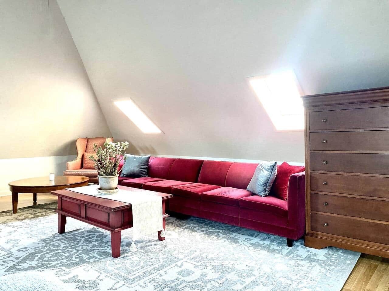A loft-style living room with a red sofa, a wooden coffee table, and a dresser.