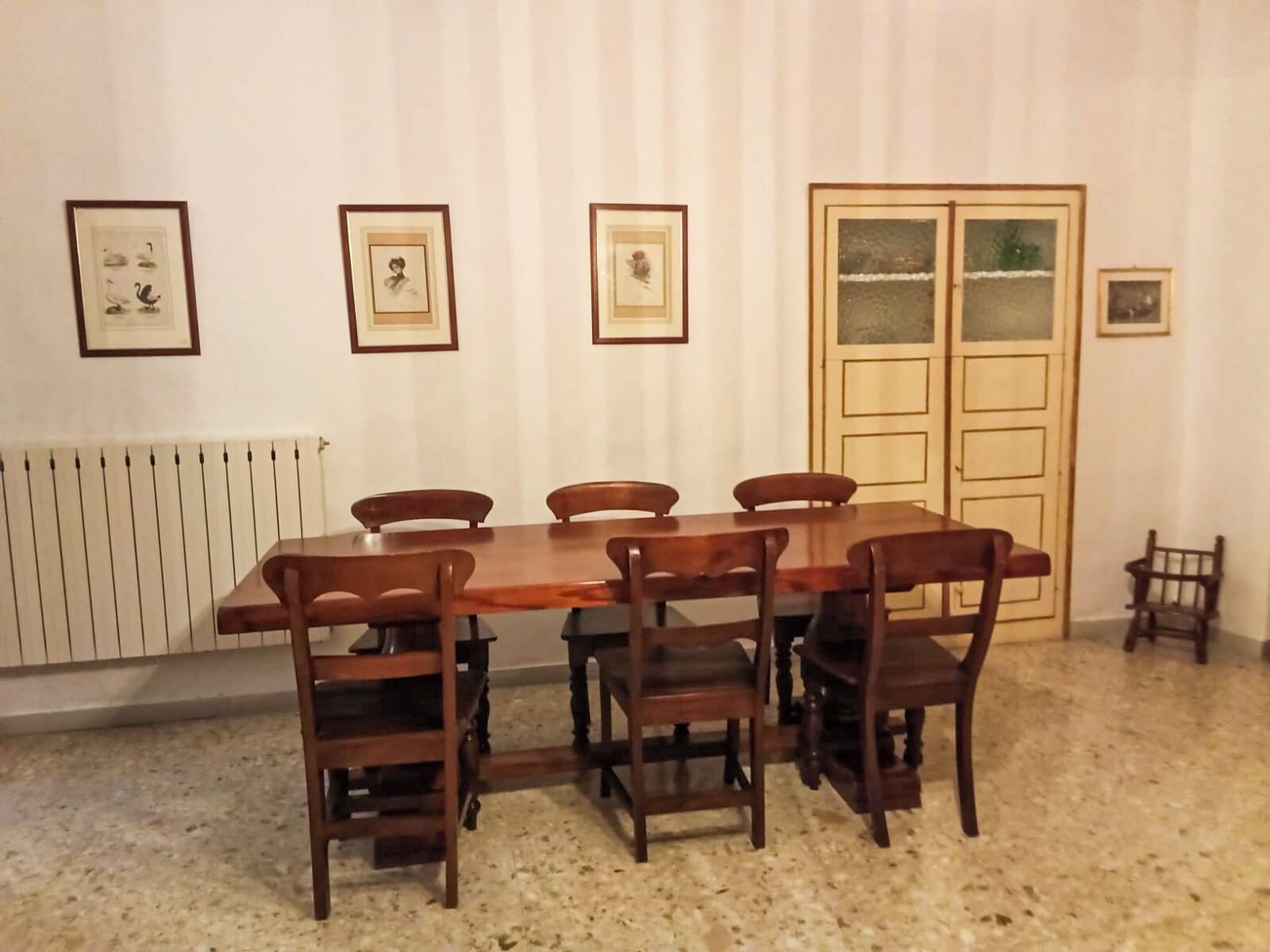Un comedor con una mesa de madera rectangular, seis sillas e imágenes enmarcadas en la pared.