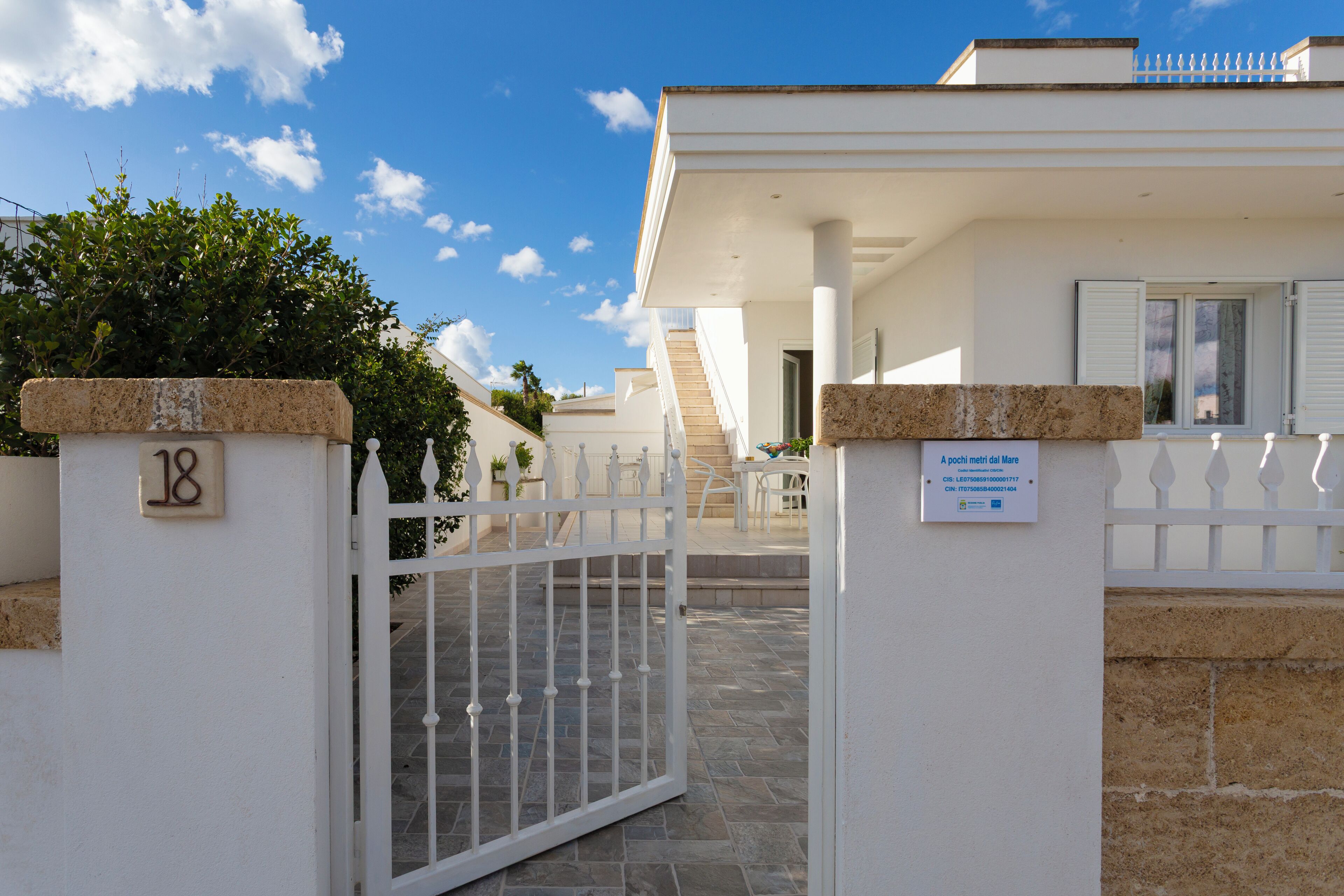 A gated entrance to a building with a stone pillar marked '18'.