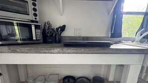 A kitchen with a built-in microwave, a toaster, and a coffee maker. There are various utensils and containers on the countertop.