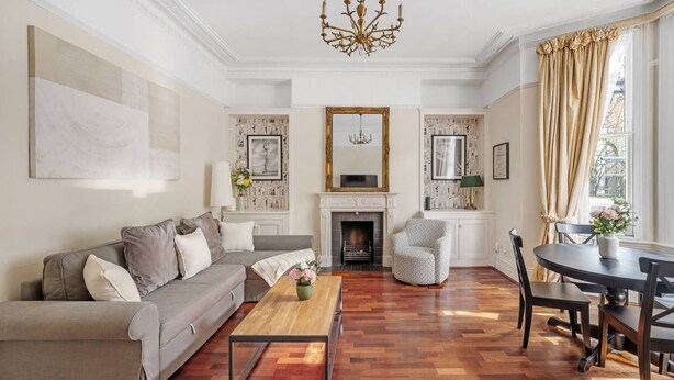 A living room with a sofa, coffee table, fireplace, and dining area. - 1 Bed Flat in Earl\'s Court (Greater London)