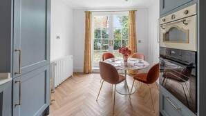 A kitchen with a dining table, chairs, and an oven. - Blossom House New 3Bed house in Barons Court (Greater London)