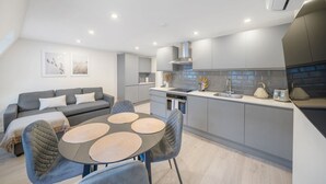 A modern kitchen with grey cabinets, a built-in oven, and a stainless steel range hood. - New 1Bed with AC near Portobello (Greater London)