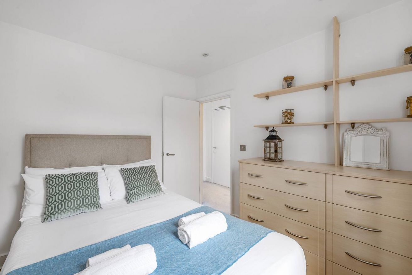 A hotel room with a bed, a dresser, and a mirror.