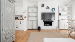 A modern living room with a large flat-screen TV, white cabinetry, and a fireplace. - New 2Bed with Air Con in Kensington (London)