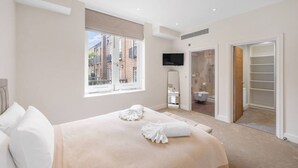 A modern bedroom with a large bed, a TV, and a walk-in closet. - New 3Bed in Knightsbridge (Greater London)