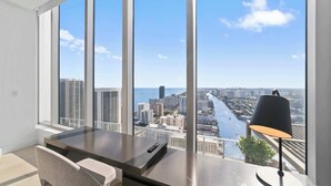 A modern room with a large window, a desk, a chair, and a lamp. - 2BR Ocean Penthouse: Private Terrace & Hot Tub (Hollywood)