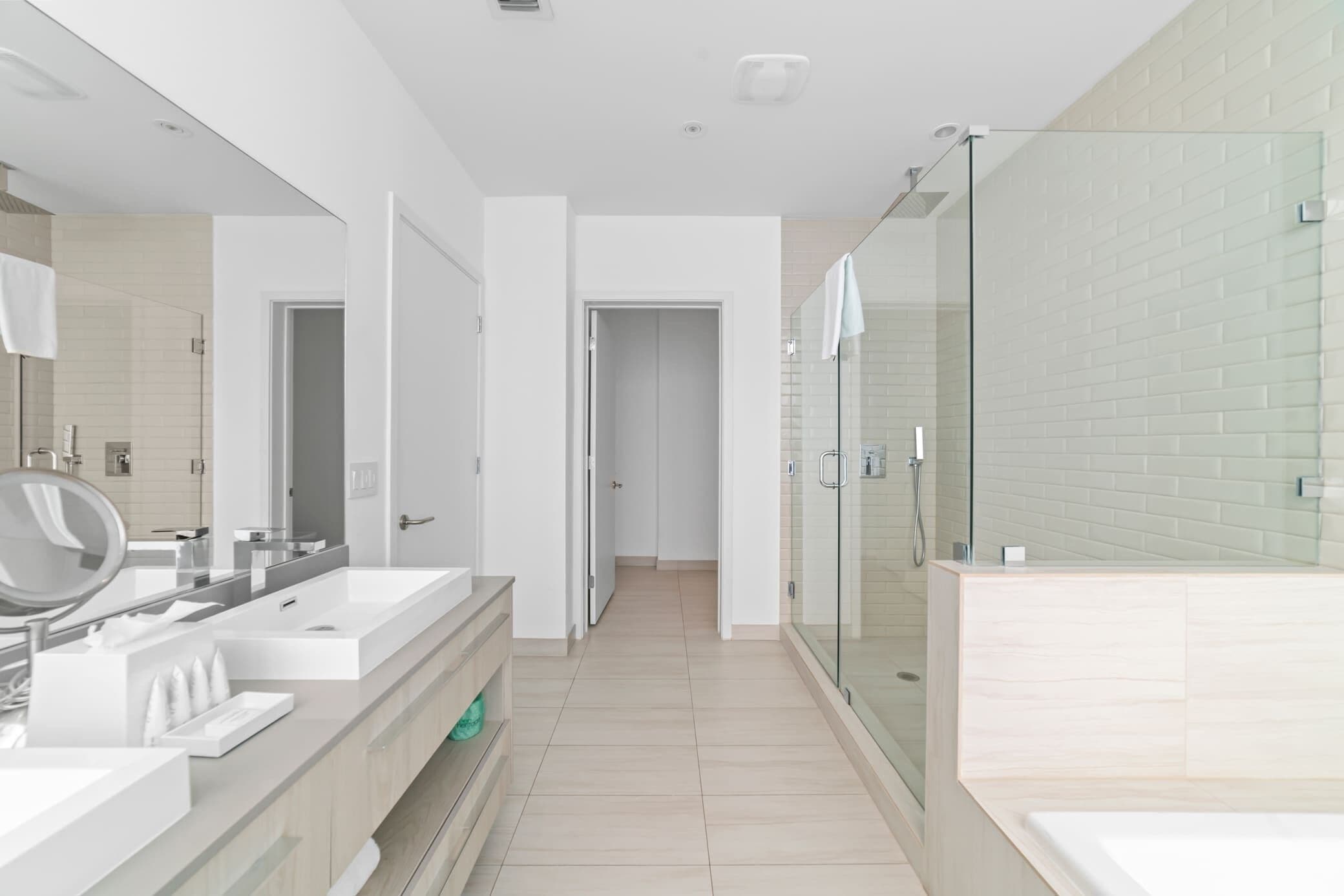 A modern bathroom with a glass-enclosed shower, a large mirror, and a vanity with a sink and countertop.