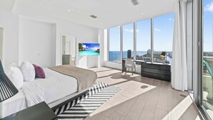 A modern bedroom with a large bed, a TV, and a city view. - 2BR Ocean Penthouse: Private Terrace & Hot Tub (Hollywood)