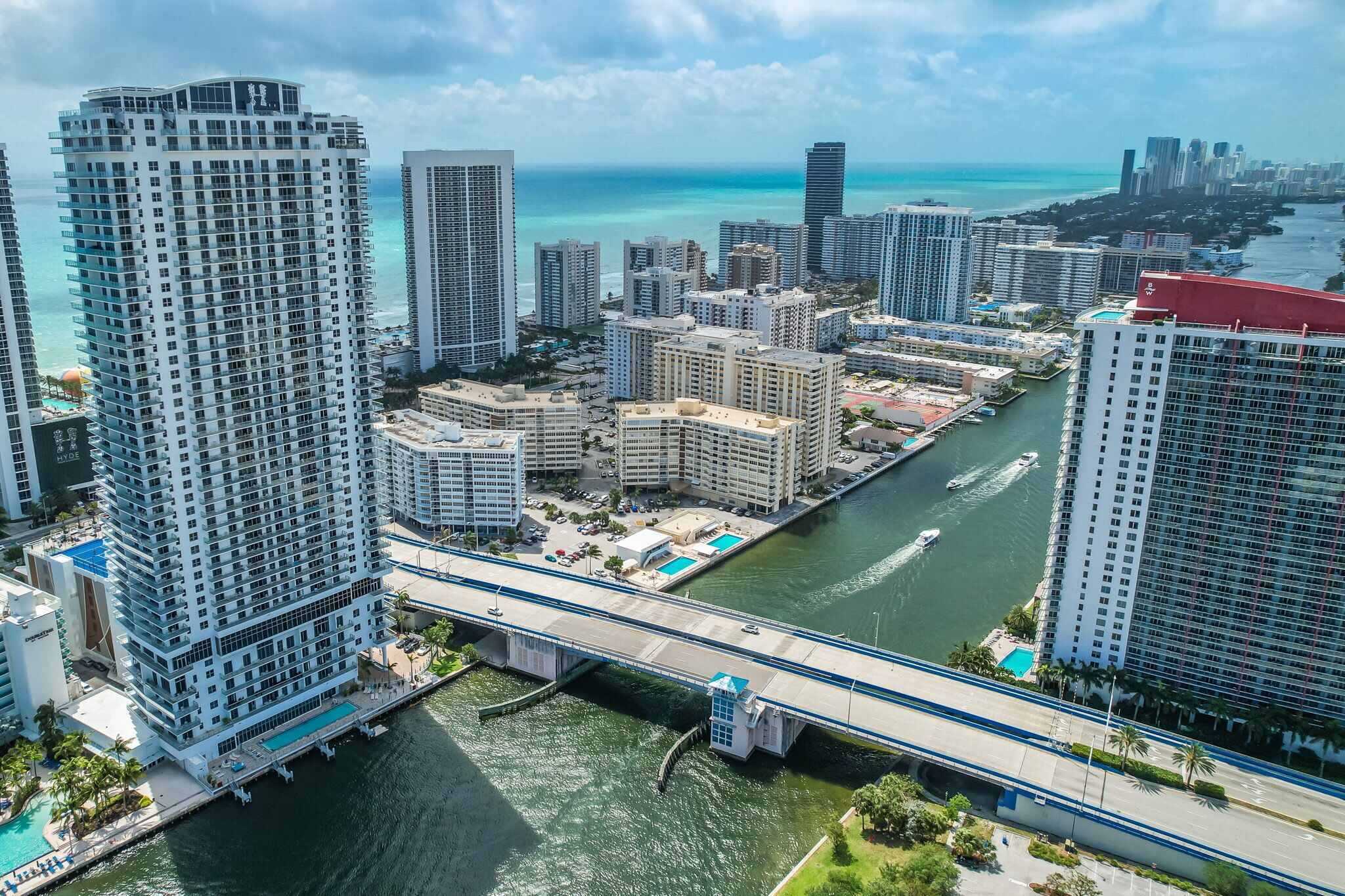 A high-rise hotel with a view of the ocean and a bridge.