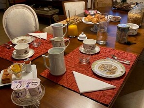 Una mesa de desayuno dispuesta con diferentes platos, incluyendo una jarra, tazas y un plato de pasteles.