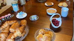 Un buffet de petit-déjeuner proposant un assortiment de viennoiseries, de confitures et de fruits.