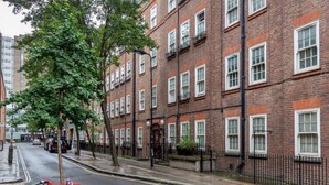 A red bicycle parked on a street with brick buildings and trees. - New 2Bed apartment in Covent Garden (London)