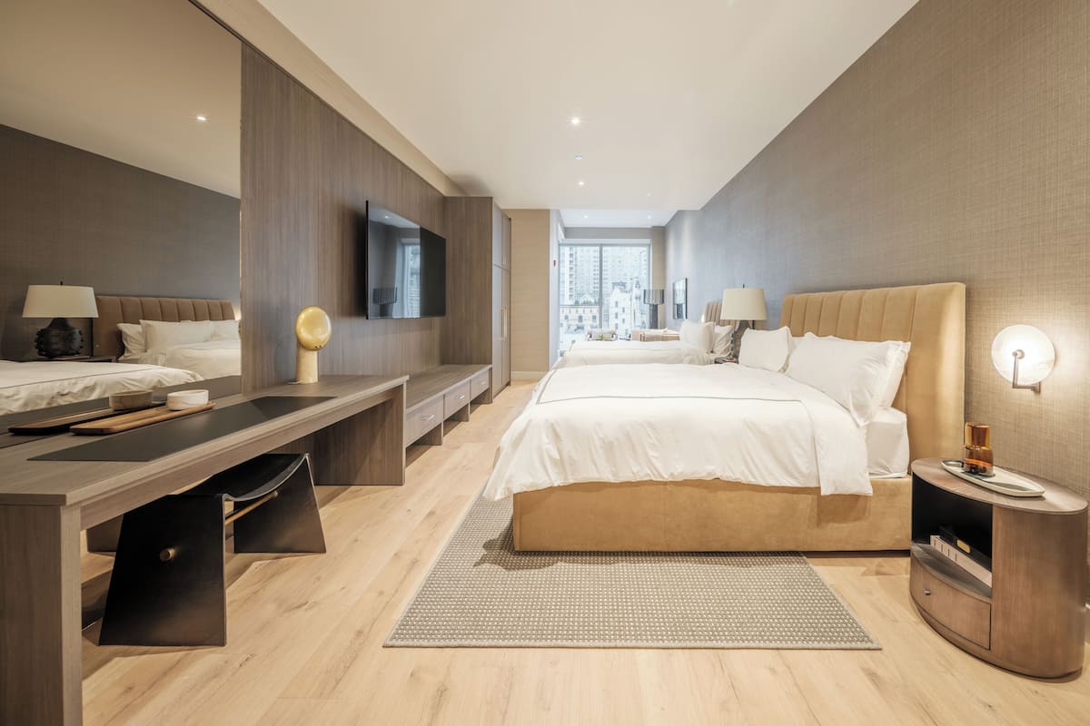 Ein modernes Hotelzimmer mit einem großen Bett, einem Schreibtisch und einem Fernseher.