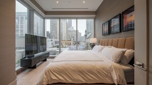 Ein modernes Schlafzimmer mit einem großen Bett, einem Fernseher und Blick auf die Stadt.