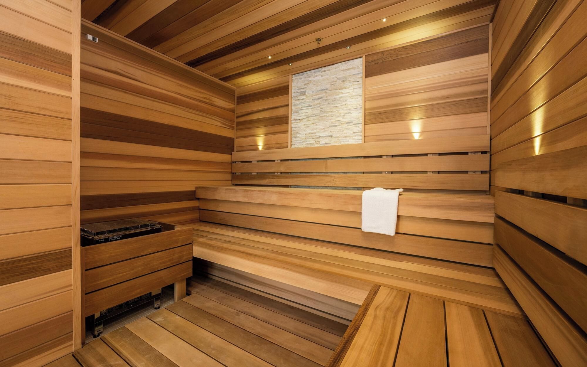 A sauna room with wooden slats, a bench, and a towel rack.
