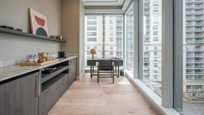 Eine moderne Küche mit großem Fenster, Holzschränken und einem Essbereich mit Tisch und Stühlen.