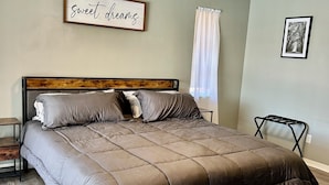 A bedroom with a bed, a ceiling fan, a framed picture, and a wall-mounted sign. - 3-bedroom & den house in welcoming Cape Coral with Pool, centrally located!🌴 (Cape Coral)