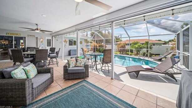 A modern living room with a pool, large windows, and ceiling fans. - 3-bedroom & den house in welcoming Cape Coral with Pool, centrally located!🌴 (Cape Coral)