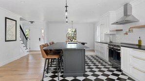 A modern kitchen with a central island, white cabinetry, and a black and white checkered floor. - Cozy North Fork Home Close to Beaches, Wineries, and Town, Perfect for Families (East Marion)