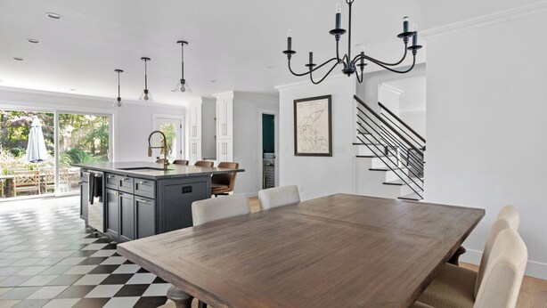 A modern kitchen with a large island, pendant lighting, and a staircase leading to an upper level. - Cozy North Fork Home Close to Beaches, Wineries, and Town, Perfect for Families (East Marion)