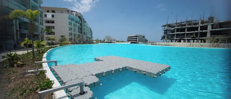 Una piscina con zona de deck integrada, rodeada de edificios modernos y palmeras.