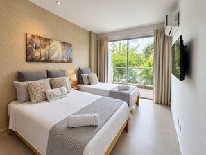 Hotellihuone, jossa on kaksi sänkyä, suuri ikkuna, taulu seinällä ja litteänäyttöinen televisio.