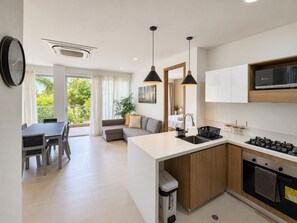 A modern kitchen with a central island, a dining area with a table and chairs, and a living area with a sofa and a plant. - Baia Kristal Prive | 2 Bedrooms | Sleeps 8 | P31L (Cartagena de Indias)