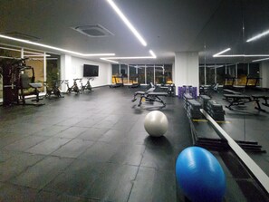 Une salle de sport équipée de matériel d’exercice, d’un grand ballon de gymnastique et de miroirs sur les murs.