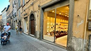 A cobblestone street with a boutique store displaying handbags.