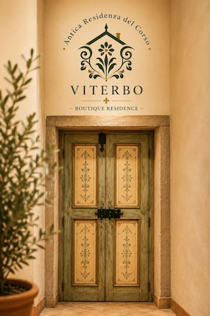 A door with a decorative design and the text 'Antica Residencia del Corso Viterbo - Boutique Residence' above it.