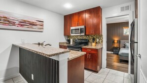 Una cocina moderna con encimeras de granito, microondas, estufa y armarios de madera.