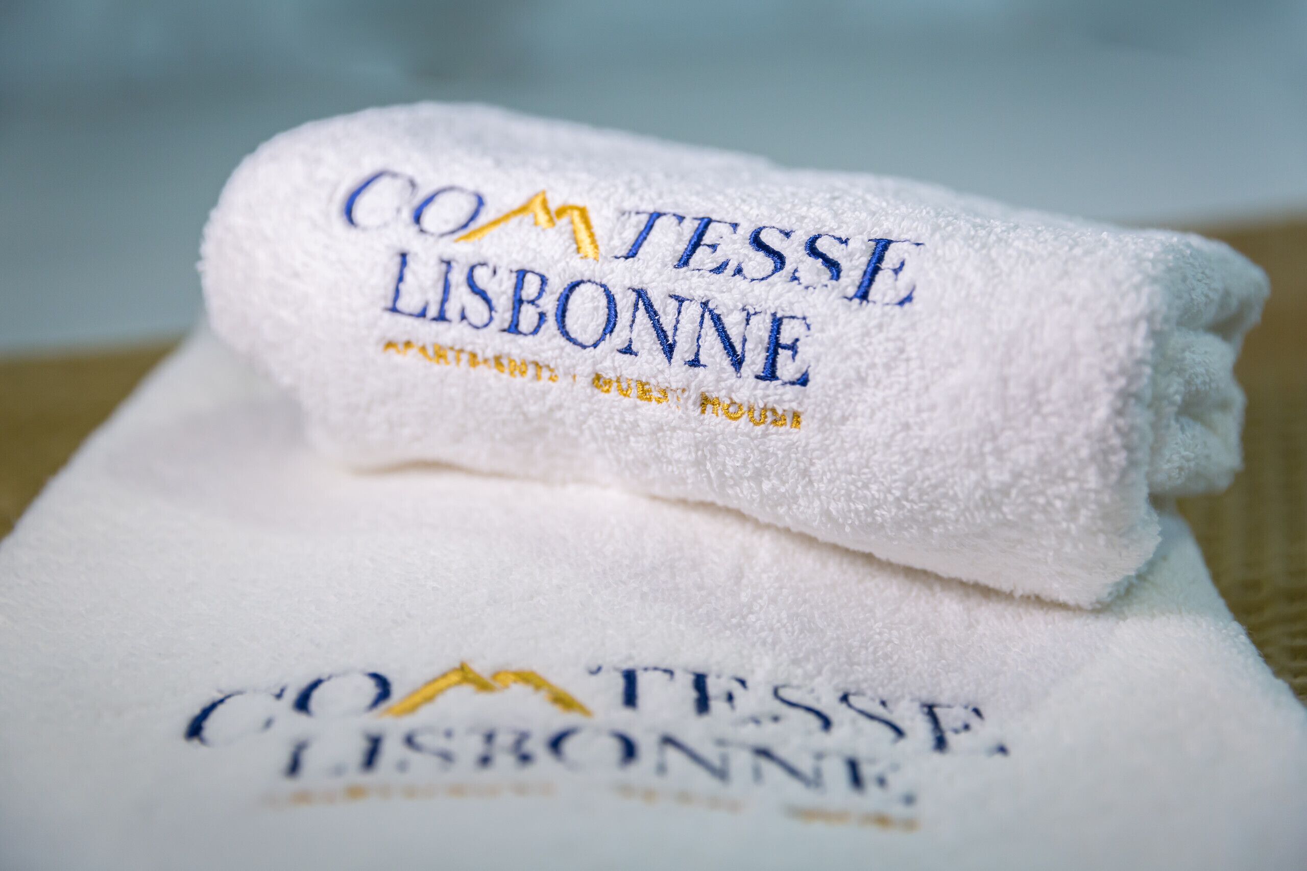 Två vita handdukar med broderad text som lyder "Comtesse Lisboa" och "Moulin de la Tour".